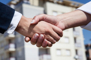 a company executive and employee shake hands before discussing the FMLA harassment the employee faces