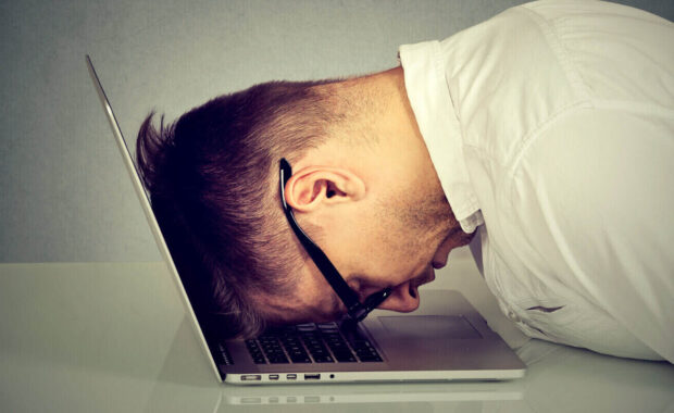 stressed young man resting head on laptop keyboard