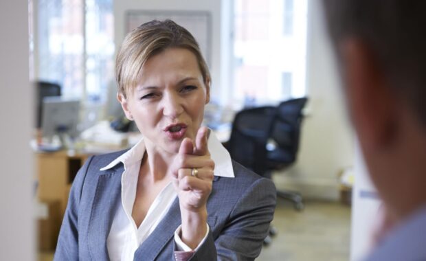 aggressive businesswoman shouting at male colleague