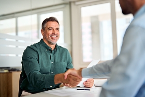 HCM subject matter expert shaking hands with client in green collared shirt