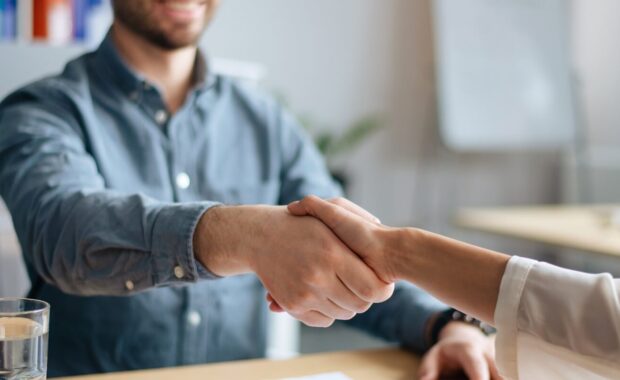 view of human resources manager shaking hands with successful vacancy applicant at office